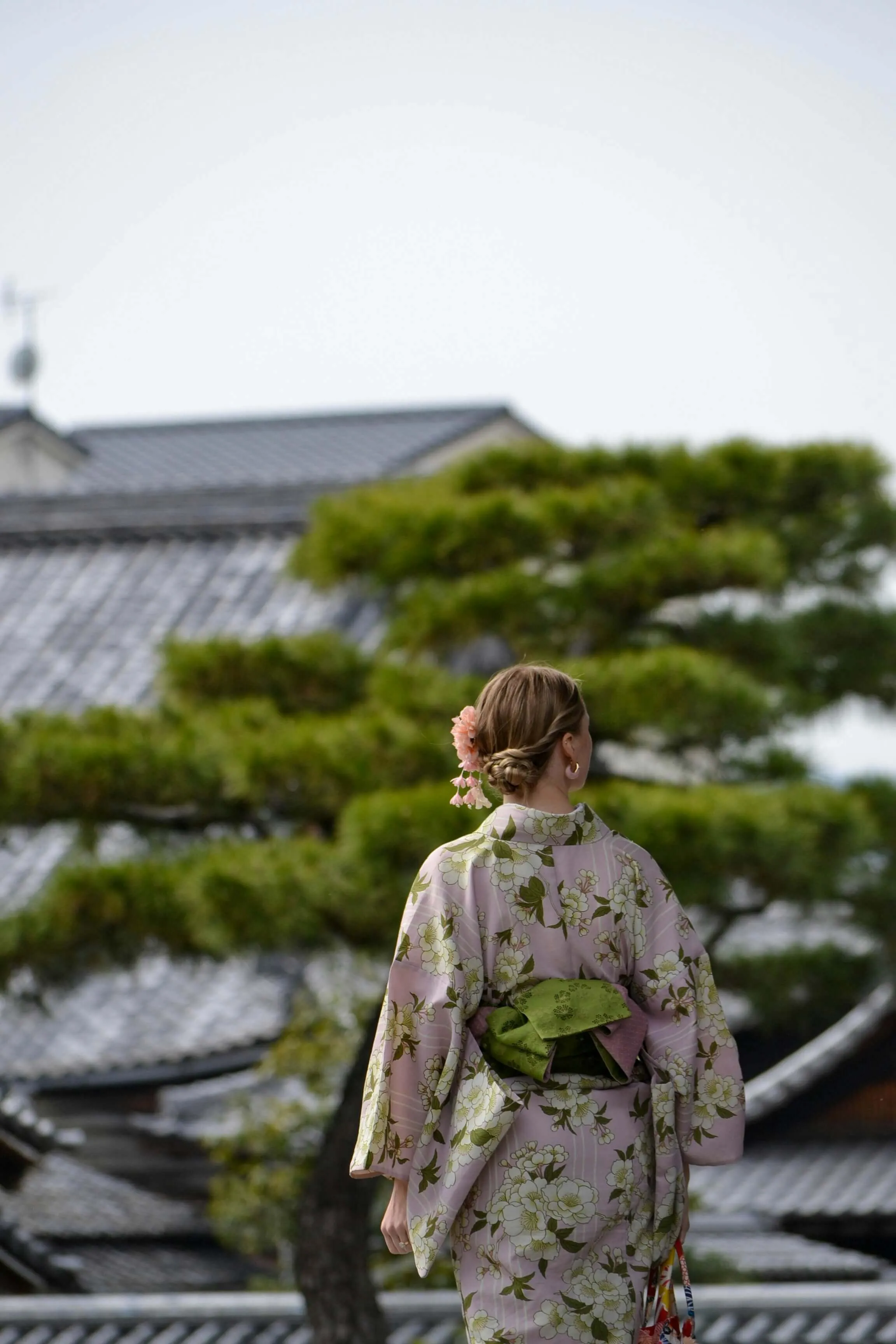 Woman in kimono seen from behind, looking out over the streets of Kyoto