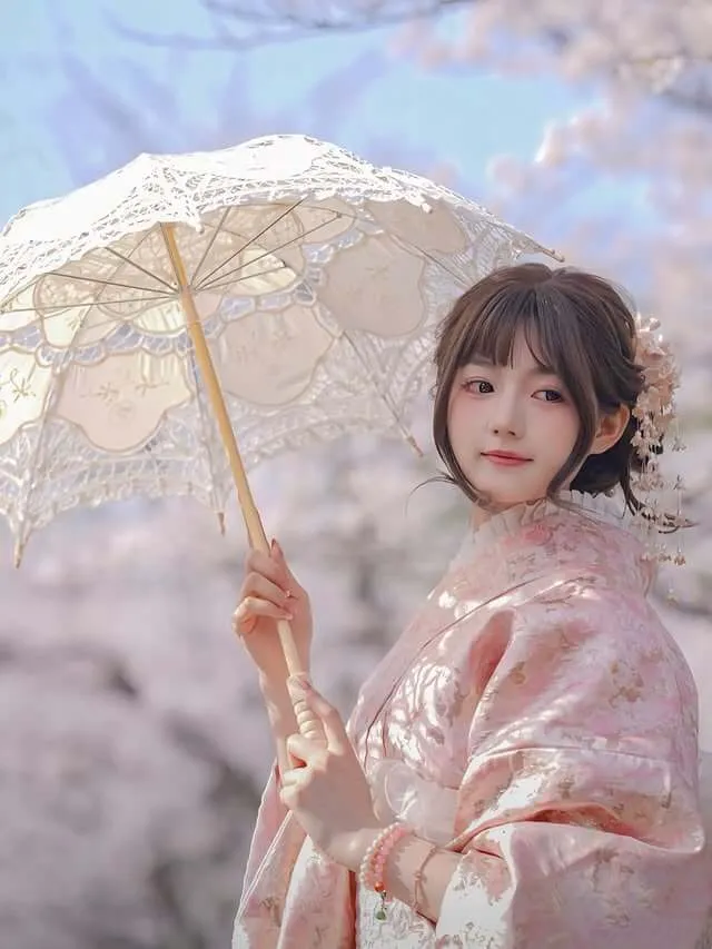 Woman in kimono holding a lace parasol under cherry blossoms